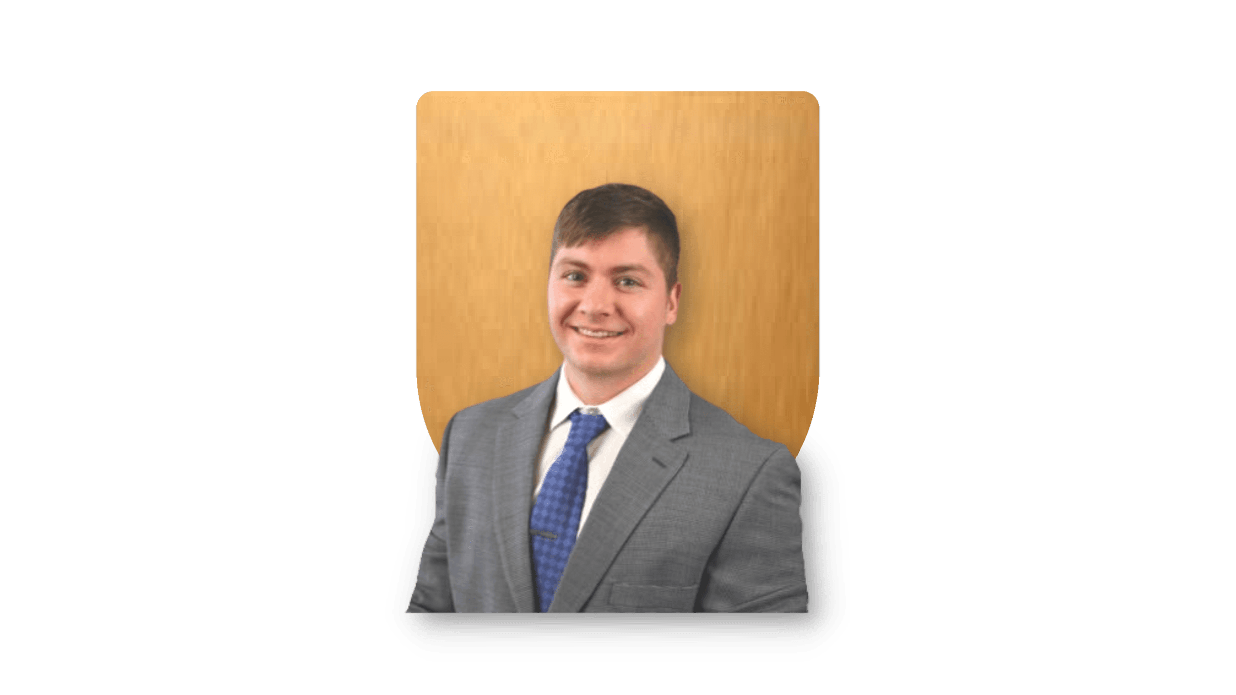 Man in a gray suit with a blue tie against a wooden background.