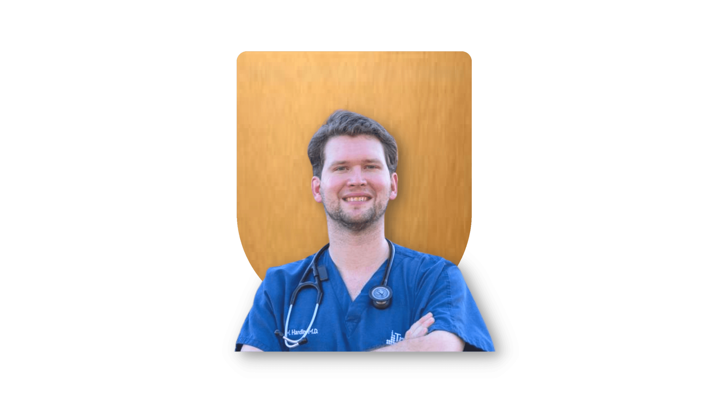 A person in blue medical scrubs with a stethoscope around their neck, standing in front of a wooden background.
